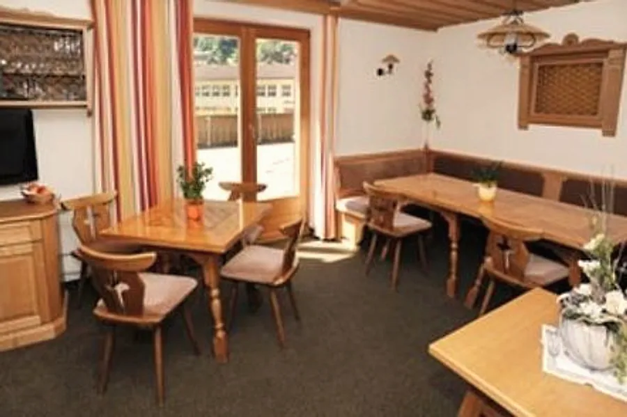 Frühstücksraum mit Holztischen, Eckbank und Blick durch die Glastür